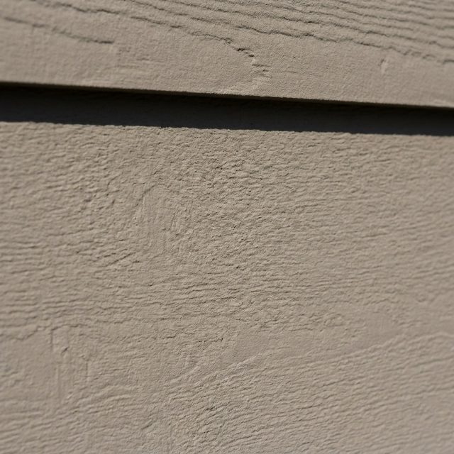 Fiber cement lap siding surface in warm greige with a board shadow line