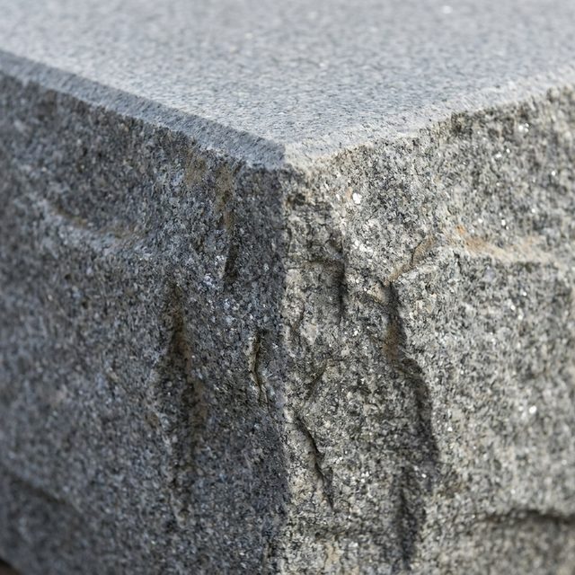 Split face grey granite step edge with a sawn flat top